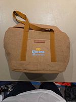 Front view of tan Corona Sunbrew insulated cooler bag showing handles and logo