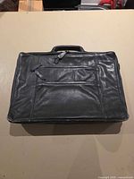 Front view of black leather briefcase showing exterior condition and front zip pocket