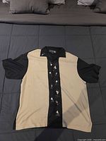 Front view of shirt laid flat showing color block design and embroidery