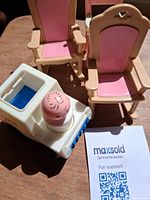 Two of the beige-and-pink chairs alongside the white/blue toy vehicle and attached driver figure