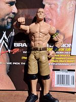 Front view John Cena action figure standing against magazine cover