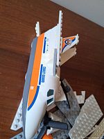 Side view of partial airplane fuselage showing Coast Guard decal, orange stripe and propeller