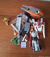 All loose LEGO parts spread on surface including partial spacecraft builds and minifigure