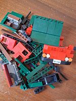 Pile of mixed LEGO pieces including green, red, black elements