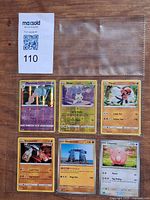Overall view of six Pokémon cards in binder sleeve with MaxSold lot tag