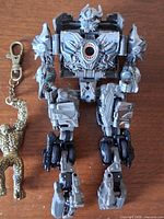 Full view of Transformers action figure beside The Thing keychain