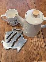 Teapot, mug and trivet grouped on wooden surface