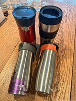 Four Contigo stainless steel travel mugs showing colors and overall wear