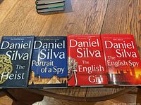 Four Daniel Silva hardcover books lined side-by-side