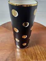 Full view of vase showing black body with gold and white polka dots