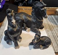 Group view of all three black unicorn figurines showing poses and gold chain collars