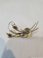 Front view of gold filled floral brooch showing blue center stone and red rhinestone buds
