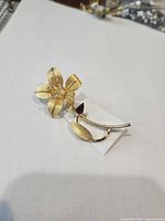 Front view of gold-tone sterling silver floral brooch with purple rhinestone