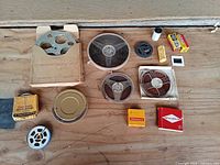 Overview of all film reels, canisters, boxes and slide on wooden surface