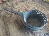 Angled view showing pan, vented rim, and turned wood handle