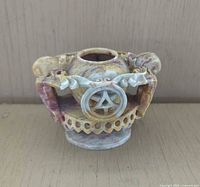 Front view of carved soapstone urn showing openwork base, scroll handles and mouse figures