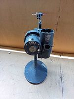 Front view of projector on stand showing lens housing, controls, and overall form