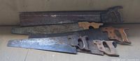 Four vintage hand saws stacked showing full blades and handles