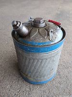 Full view of cylindrical galvanized gas can with blue bands, spout, cap, red-grip handle