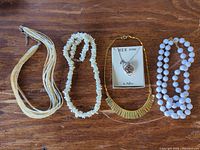 Group shot of all five necklaces laid out on wood surface