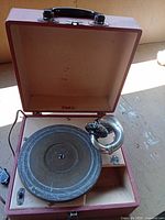 Open case showing turntable platter, tonearm with horn, interior compartment
