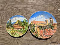 Both porcelain plates side by side showing relative sizes and painted scenes
