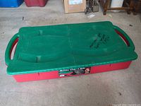 Full view of closed red under-bed storage box with green lid