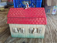 Front view showing red roof lid with rooster and animal heads at windows