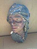 front view of plaster wall bust mask showing facial details, paint scheme and surface chips