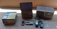 Group shot showing all items: radios, hair dryer box, two mobile phones and chargers