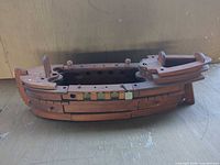 Full side view of wooden model boat showing open hull and brass accents