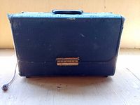 Radio closed showing exterior case with handle and AC cord