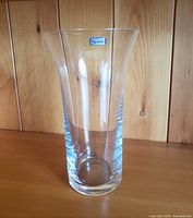 Full view of clear flared crystal vase on wooden surface