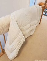 Front view of white queen down duvet draped on railing