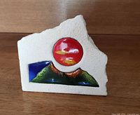 Front view showing enamel sun and mountains on concrete block