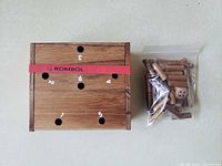 Closed wooden box showing numbered top and red elastic band next to bag of pegs and die