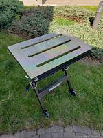 Work table unfolded on lawn showing slotted galvanized top and frame