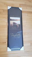 Front view of sealed black poster frame with dimensions and sample image visible