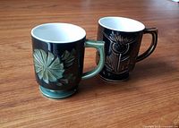 Two carved ceramic pedestal mugs on wood surface