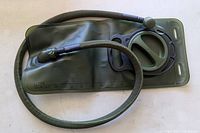 Front view of olive green hydration bladder with screw cap and drink tube attached