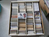 Overhead view of five-row monster box filled with hockey cards, two sleeved highlight cards on top