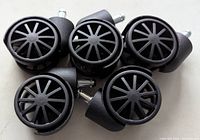 Group shot of the five black twin-wheel casters showing overall design and quantity