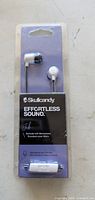 Front of sealed retail package showing Skullcandy Jib earbuds, inline remote, branding