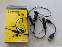 Front of yellow Skullcandy Jib+ box with black wireless earbuds and charging cable displayed