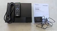 Top view of Blu-ray player with remote, HDMI cable, power adapter, manual
