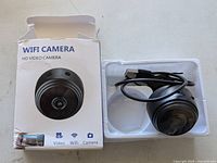 Retail box beside camera in plastic tray, shows product name and image
