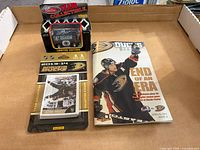Three Anaheim Ducks items laid out: sealed card pack, boxed Zamboni toy, 2014 program