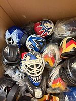 Box containing numerous mini goalie masks, some bagged