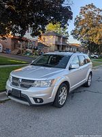 Front three-quarter view of silver 2012 Dodge Journey parked at curb