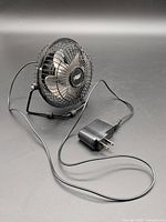 Full view of 4-inch metal desk fan with attached USB cord and wall adapter